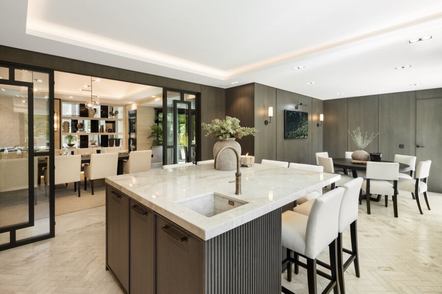 Cocina abierta y comedor en una villa de Marbella con isla de mármol y puertas de cristal