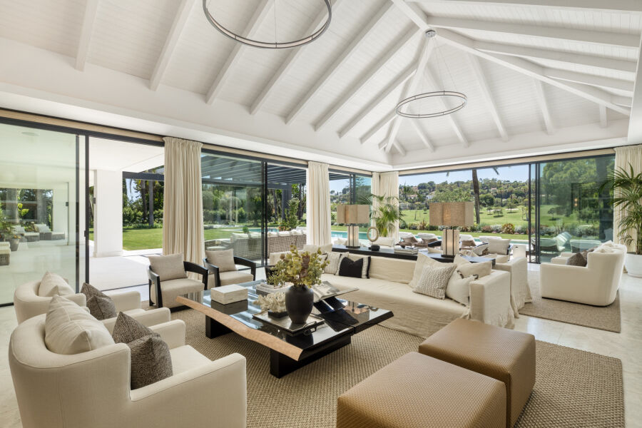 Salón diáfano de una villa en Marbella con techo blanco abovedado, grandes ventanales y vistas al golf