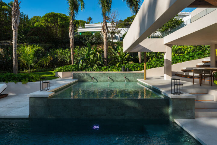 Piscine et terrasse de la villa à Nueva Andalucia avec marches, transats et jardin luxuriant