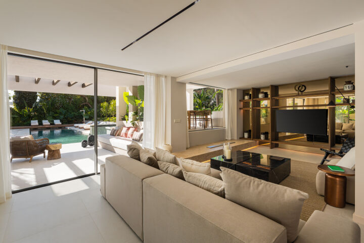 Séjour ouvert d’une villa à Marbella avec baies coulissantes sur la terrasse et la piscine
