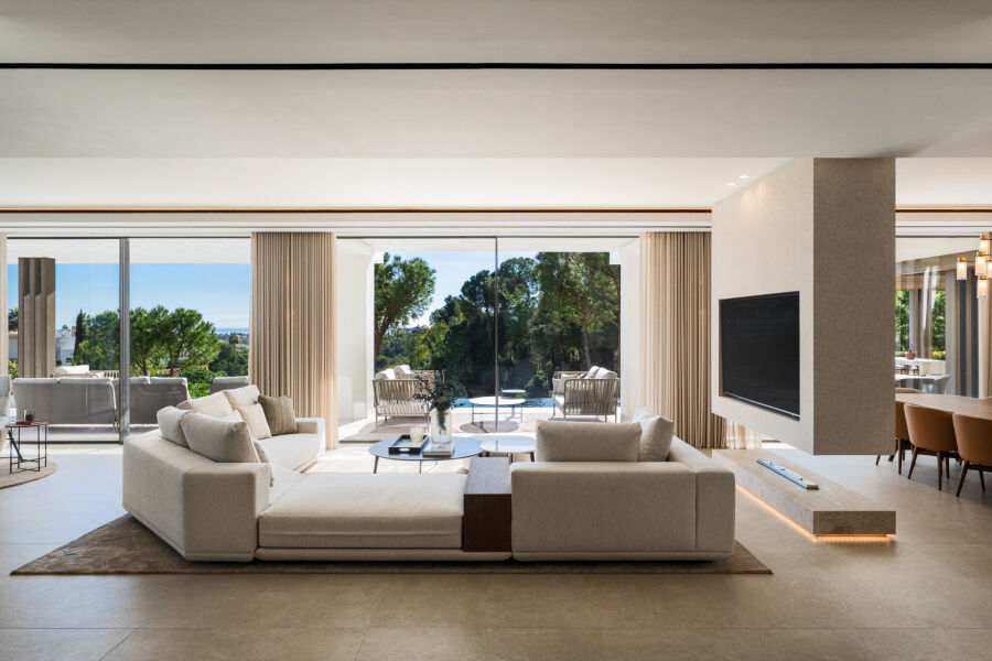 Open-plan villa living room in La Quinta, Benahavis with large sliding doors, beige sofas and pool views