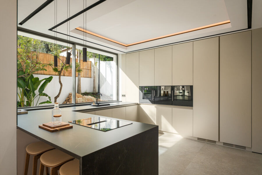 Modern kitchen in a La Quinta villa with beige cabinetry, black island and large garden window