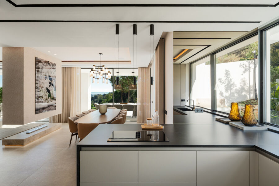 Open-plan villa kitchen and dining area in La Quinta, Benahavis, with floor-to-ceiling windows and a sea view