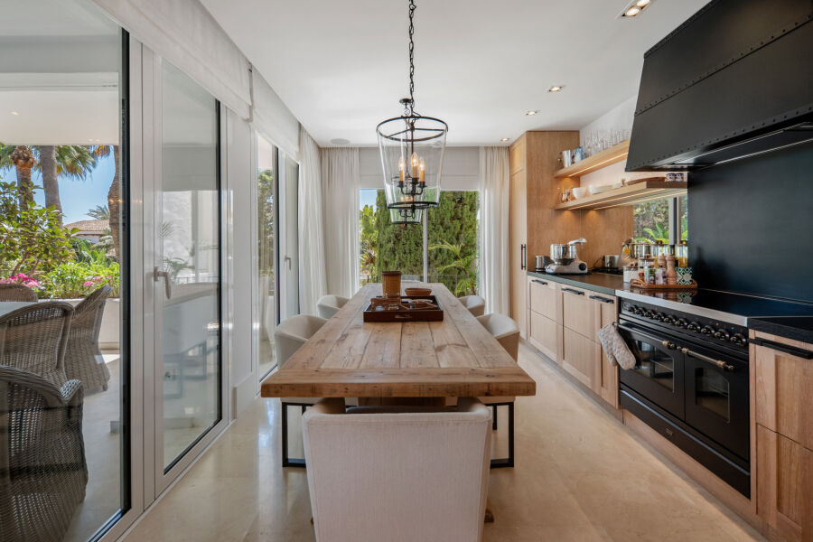 Cocina y comedor del apartamento en Marbella con mesa de madera junto a puertas correderas a la terraza