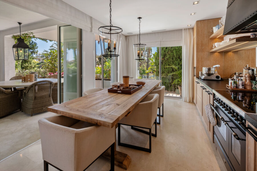 Cocina y comedor de planta abierta en un apartamento en Marbella con puertas a la terraza y vistas al jardín