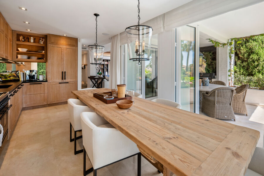 Cocina y comedor de concepto abierto con muebles de madera y puertas correderas a una terraza en Marbella