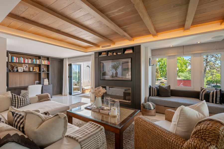 Salón de un apartamento en Marina Puente Romano, Marbella, con estanterías empotradas y chimenea