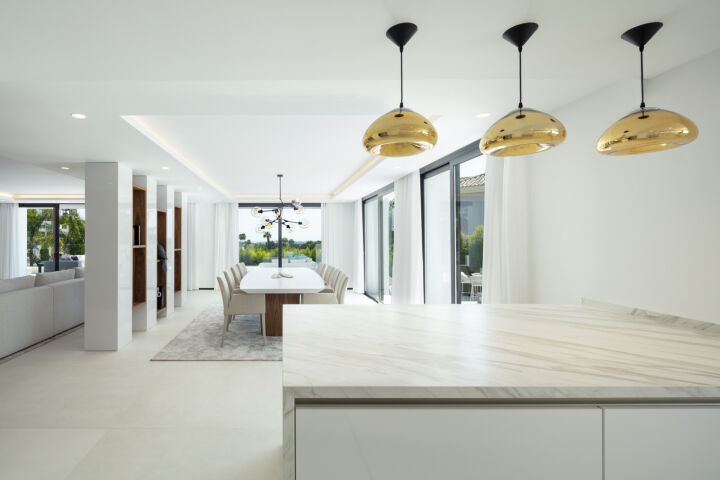 Open-plan living and dining area in a villa in Nueva Andalucia, Marbella, with marble island, white dining table and sliding